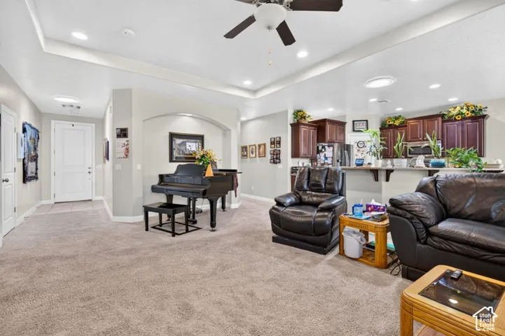 Open-concept interior featuring a recessed tray ceiling, dark wood cabinetry, a breakfast bar, and a recessed arched wall niche