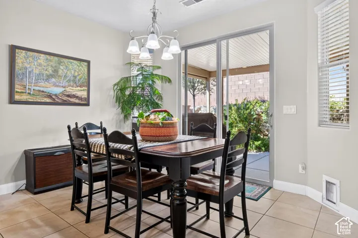 Dining area featuring neutral tile flooring, a multi-light chandelier, and large sliding glass doors providing access to a covered patio