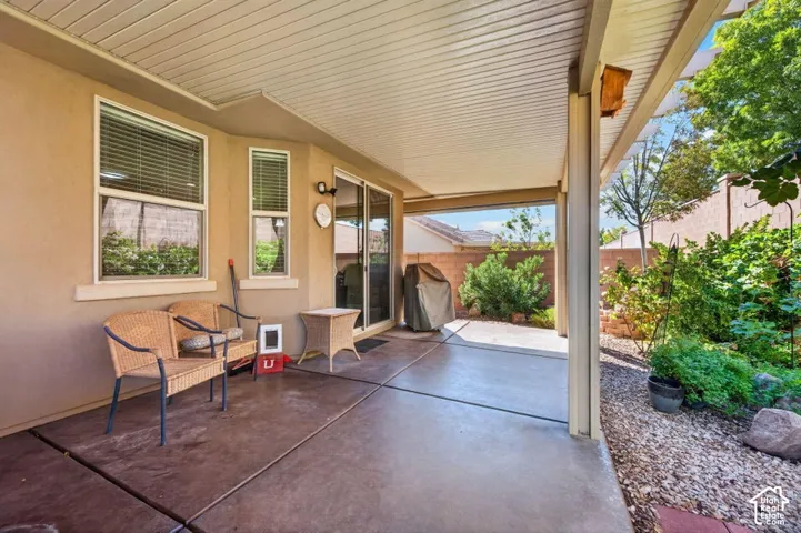 Covered patio with stained concrete flooring, corrugated metal ceiling, and multiple windows offering natural light