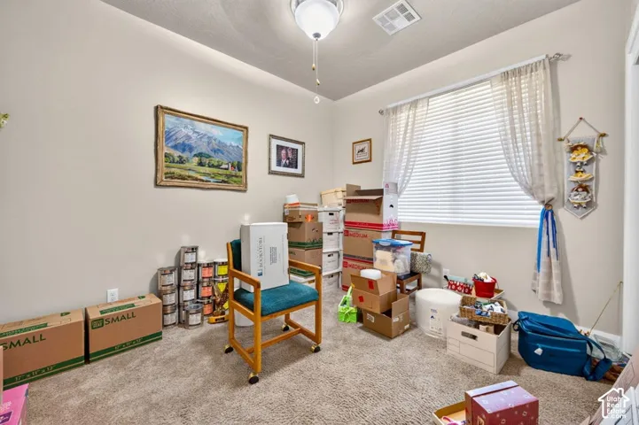 Room with neutral wall tones, carpeted flooring, and a large window fitted with horizontal blinds