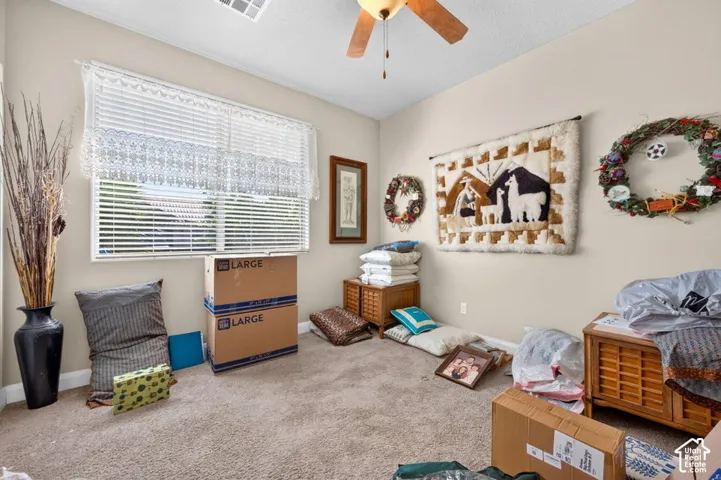 Room featuring a ceiling fan with light fixture, high-profile windows, and neutral carpeting