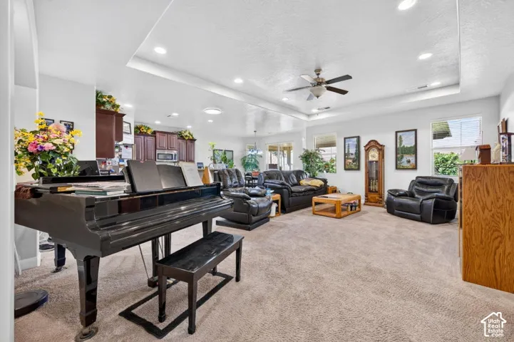Open-concept interior featuring a recessed tray ceiling, ceiling fan, recessed lighting, and wood-finish cabinetry