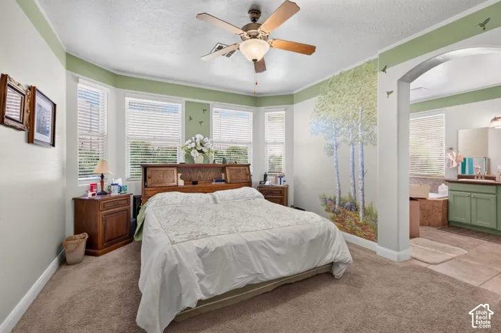 Bay window, ceiling fan with integrated lighting, arched entryway, and neutral carpeting