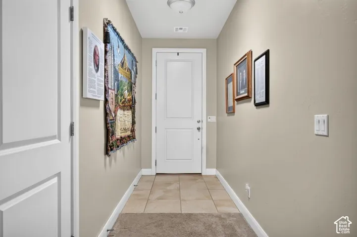 Entryway featuring neutral-toned walls, a two-panel solid core door, ceramic tile flooring, and a flush-mount ceiling light fixture