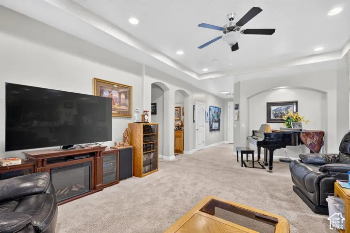 Living area featuring a tray ceiling with recessed lighting, a ceiling fan, and a decorative arched wall niche
