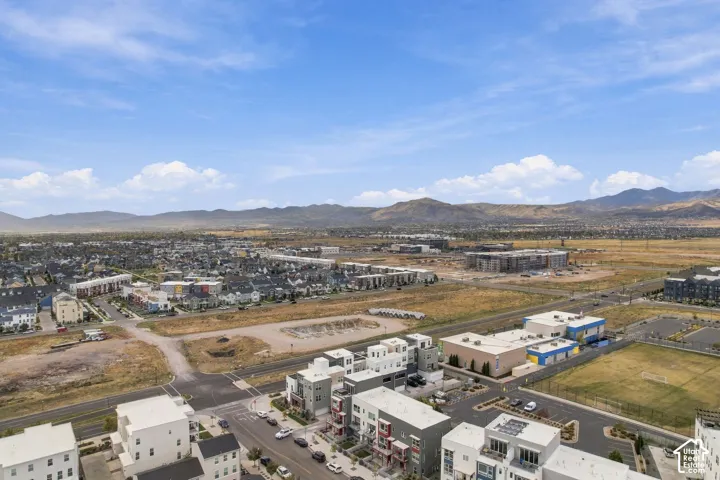 Expansive aerial perspective showcasing diverse residential developments, open land, and distant mountains under a clear sky