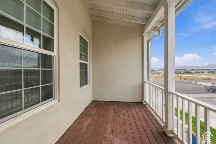 Front porch featuring plank flooring, white railing, and stucco exterior