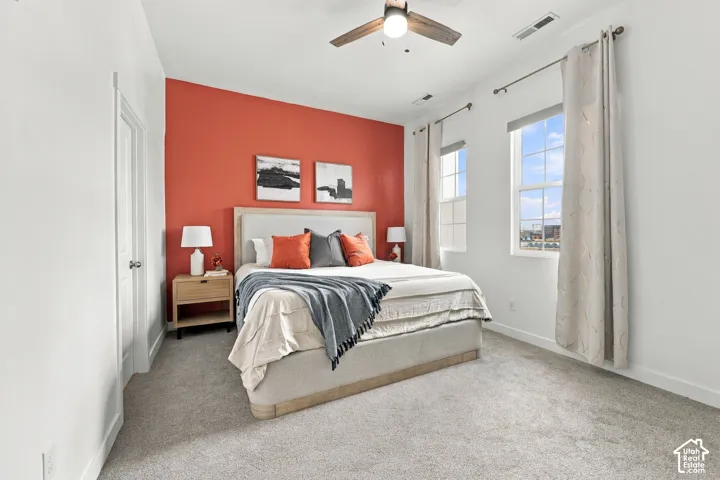 Bright interior featuring a ceiling fan, two windows, and light-colored carpeting