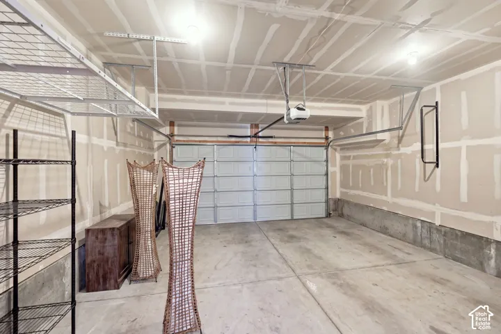 Attached garage with concrete flooring, overhead storage racks, and an automatic garage door opener