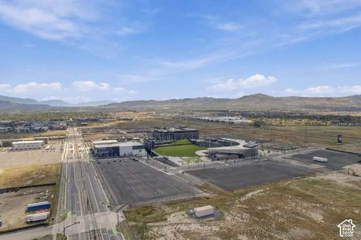 Expansive stadium facility, paved parking areas, and distant mountainous terrain under a clear sky