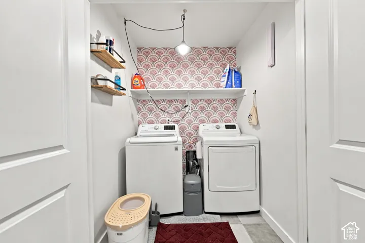 Dedicated laundry area featuring a washer and dryer, patterned wall covering, floating shelves, and recessed lighting