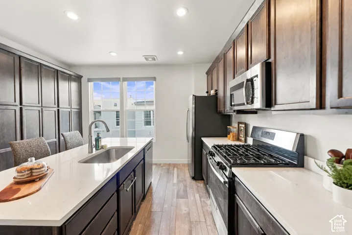 Kitchen with dark wood-finish cabinetry, light countertops, wood-finish flooring, and recessed lighting