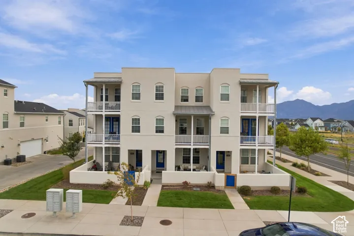Multi-level stucco exterior with multiple balconies, white railings, and blue entry doors