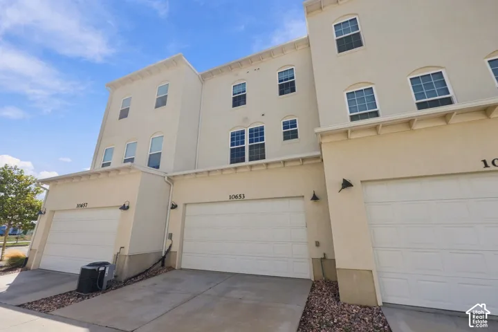 Multi-story stucco exterior featuring multiple windows and integrated garages