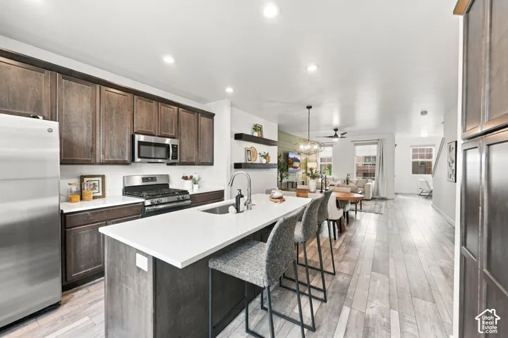 Open-concept kitchen with dark wood-finish cabinetry, stainless steel appliances, and a central island with a sink and seating