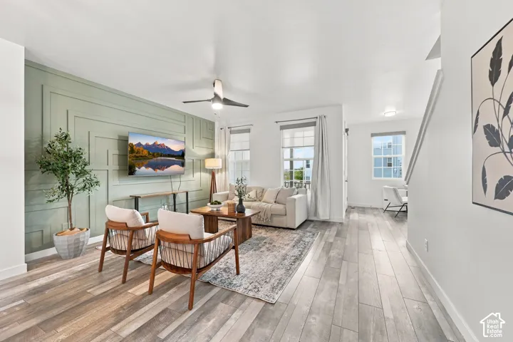 Spacious living area featuring a decorative accent wall, wood-finish flooring, recessed lighting, and multiple windows