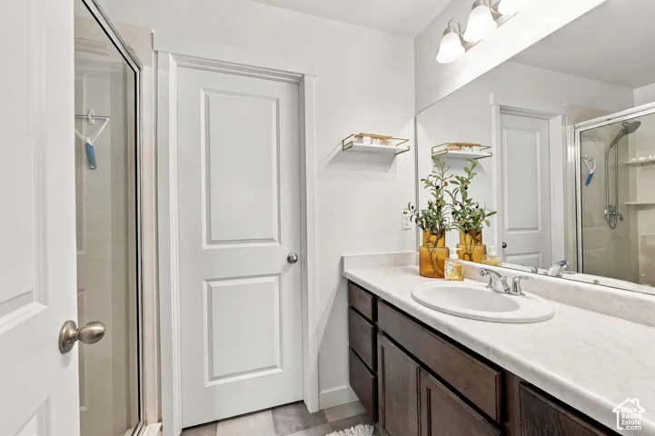 Vanity with an integrated sink and chrome faucet, dark wood-finish cabinetry, full-width mirror, and overhead vanity lighting