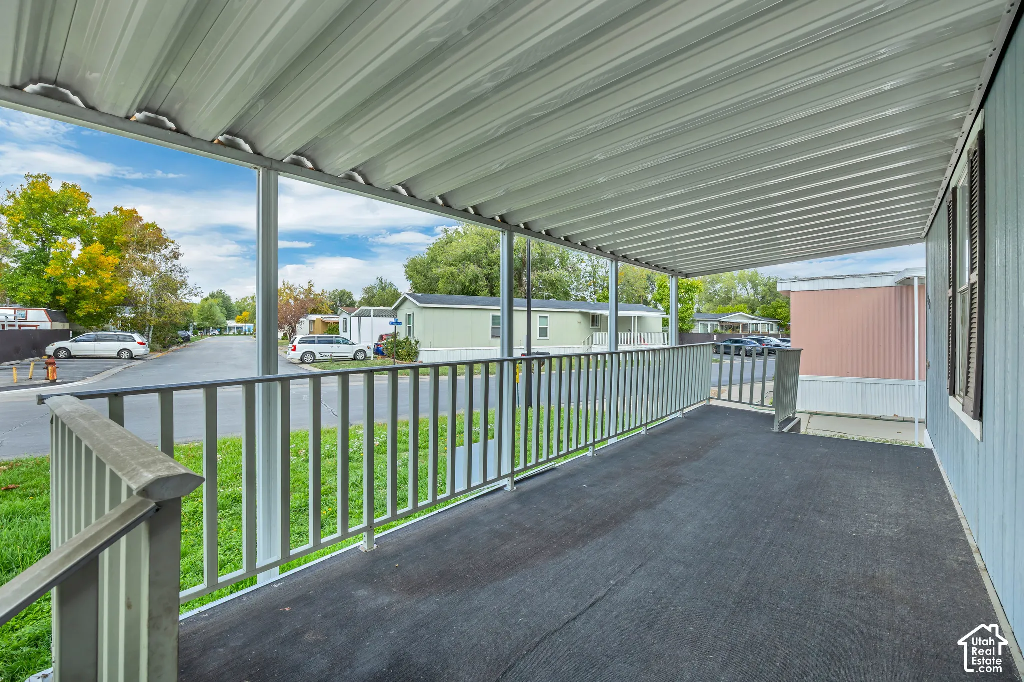 Covered porch with metal railing and light blue siding