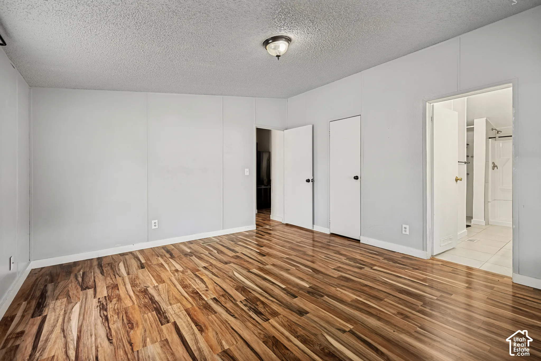 Wood-finish flooring with a textured ceiling and baseboards