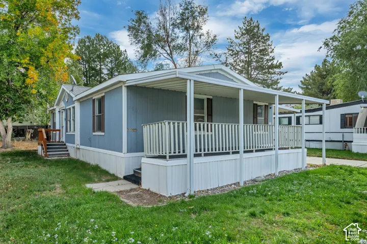 Exterior featuring light blue siding, a covered porch with white railing, and a gabled entry