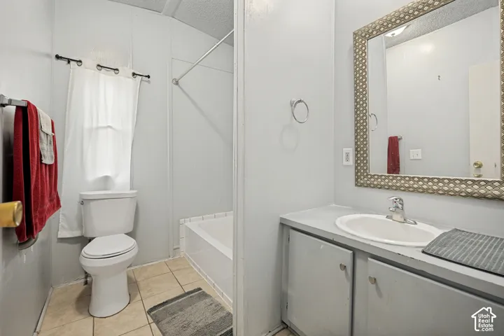 Bathroom featuring a vanity with an integrated sink, built-in lower cabinetry, a framed wall mirror, a toilet, and a shower/tub combination