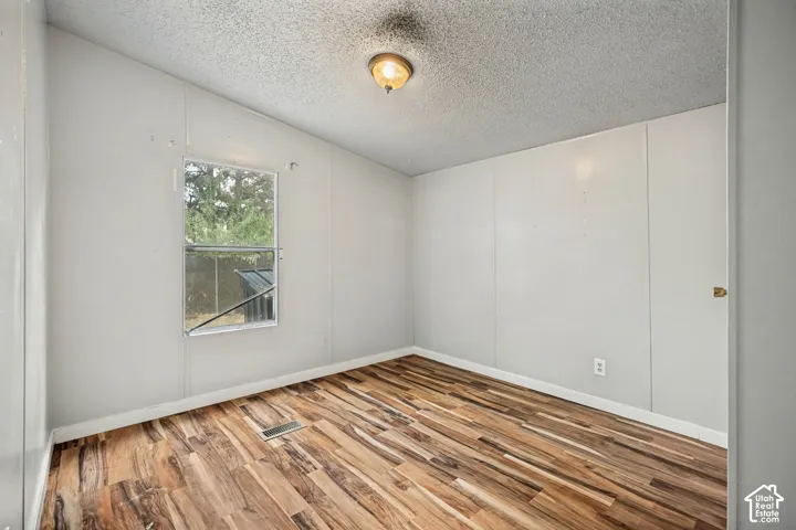 Wood-finish flooring, white panel walls, and a window with natural light