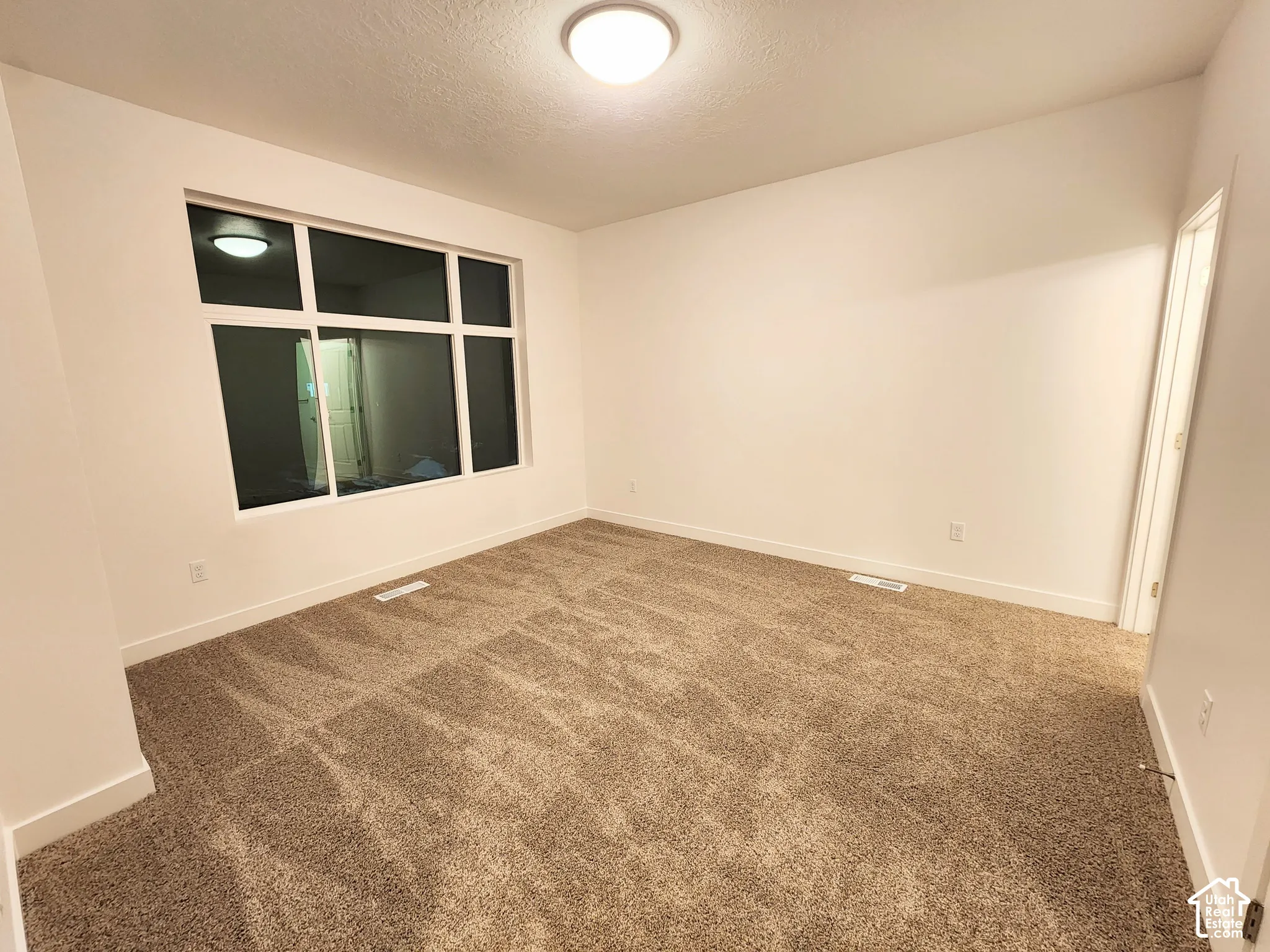 Neutral-toned wall-to-wall carpeting, expansive multi-pane window, and recessed ceiling lighting