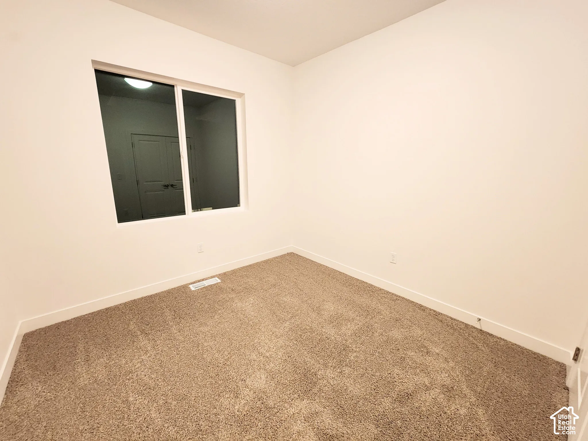 Neutral-toned carpeting, crisp white walls, and a large sliding window with white trim