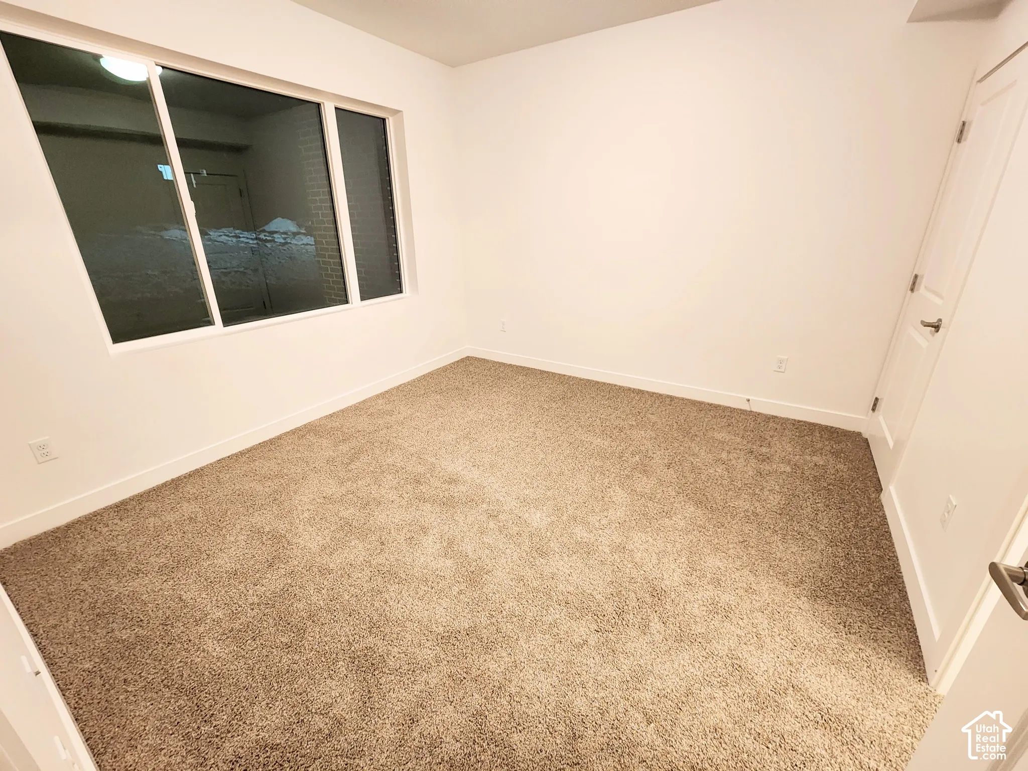 Neutral-toned carpeted flooring, white interior walls, and a large multi-pane window with a white frame