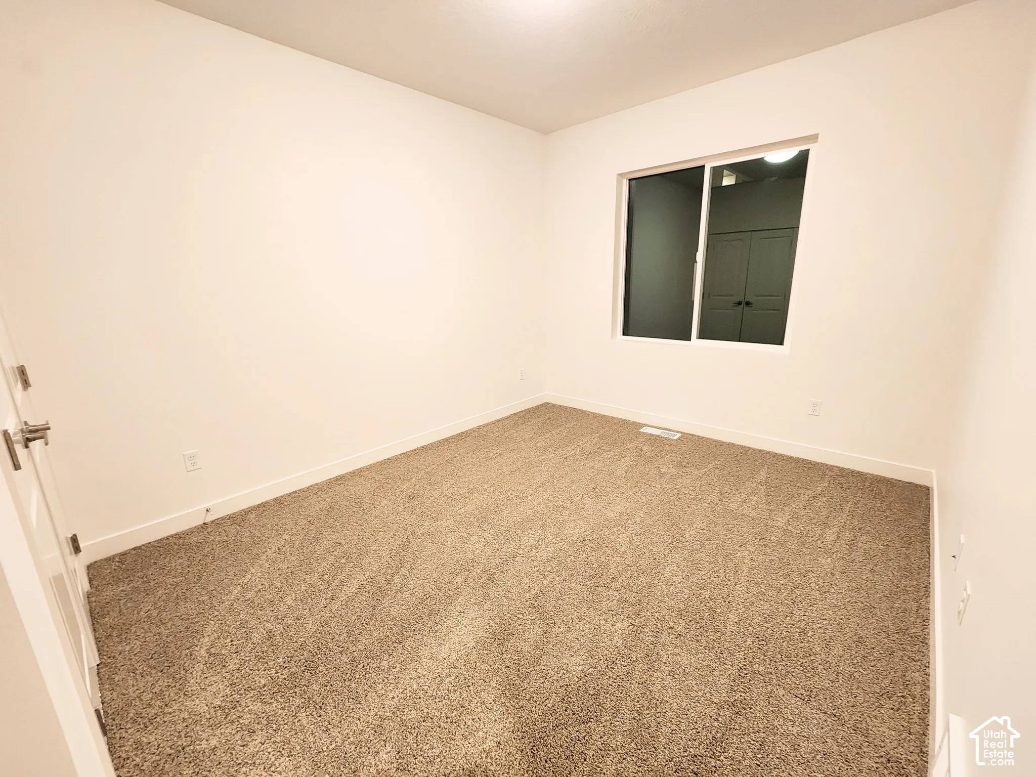 Neutral-toned carpeting, crisp white walls, and a sliding window