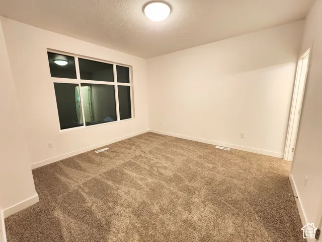 Neutral-toned wall-to-wall carpeting, expansive multi-pane window, and recessed ceiling lighting