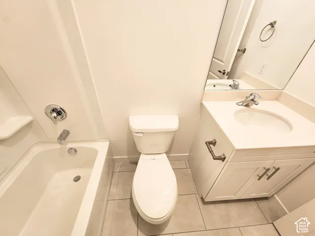 Full bathroom featuring a tub-shower combination with a chrome fixture, white vanity cabinet with an integrated sink, polished countertop, and neutral-toned tile flooring