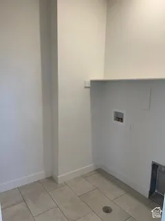 Dedicated utility area featuring tile flooring, built-in shelving, plumbing hookups, and a floor drain