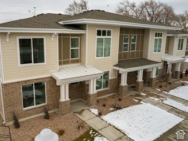 Exterior featuring horizontal lap siding, multi-tone brick masonry, decorative paneling, shingle roofing, and covered entryways supported by square columns