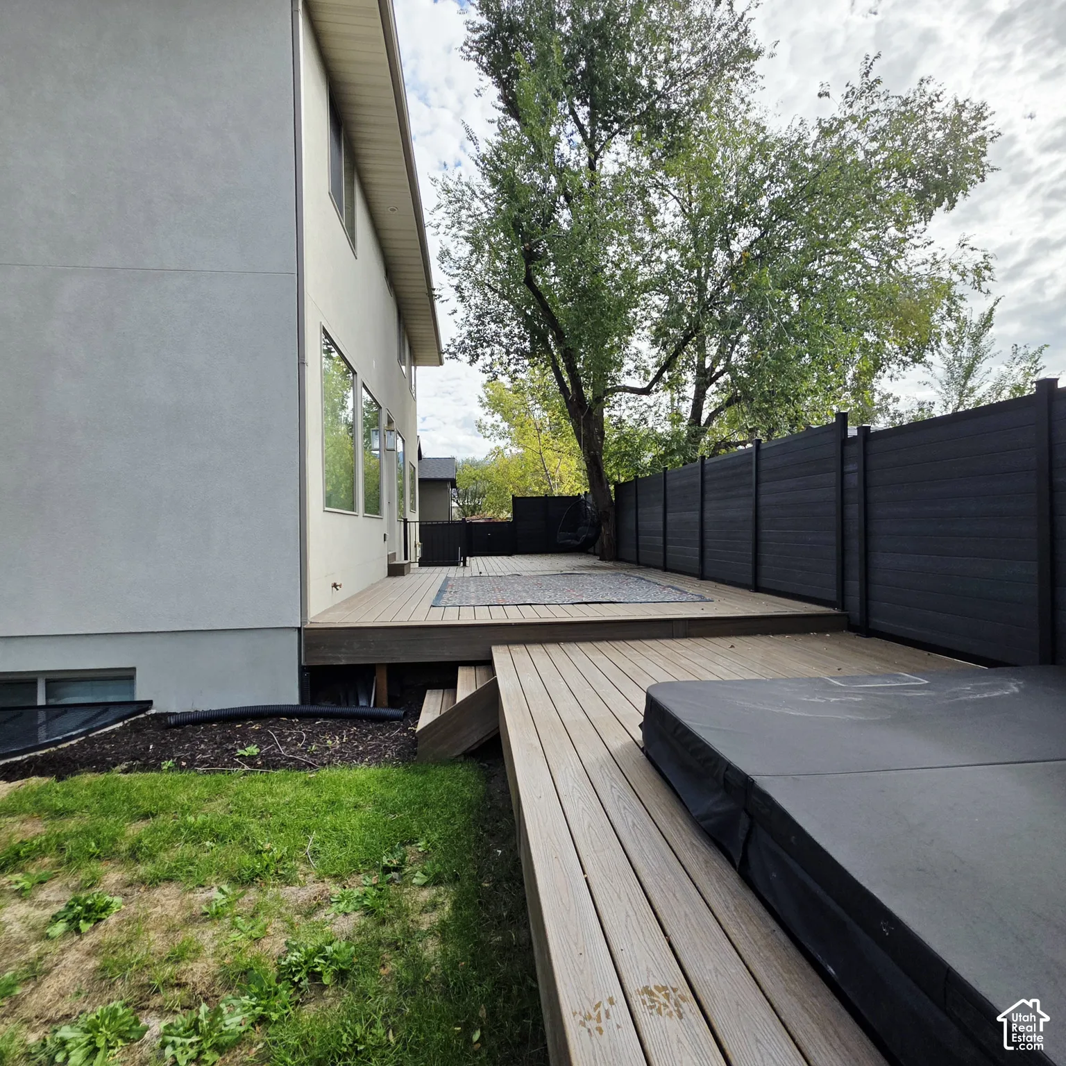 Multi-level composite decking, dark-toned privacy fencing, and built-in hot tub