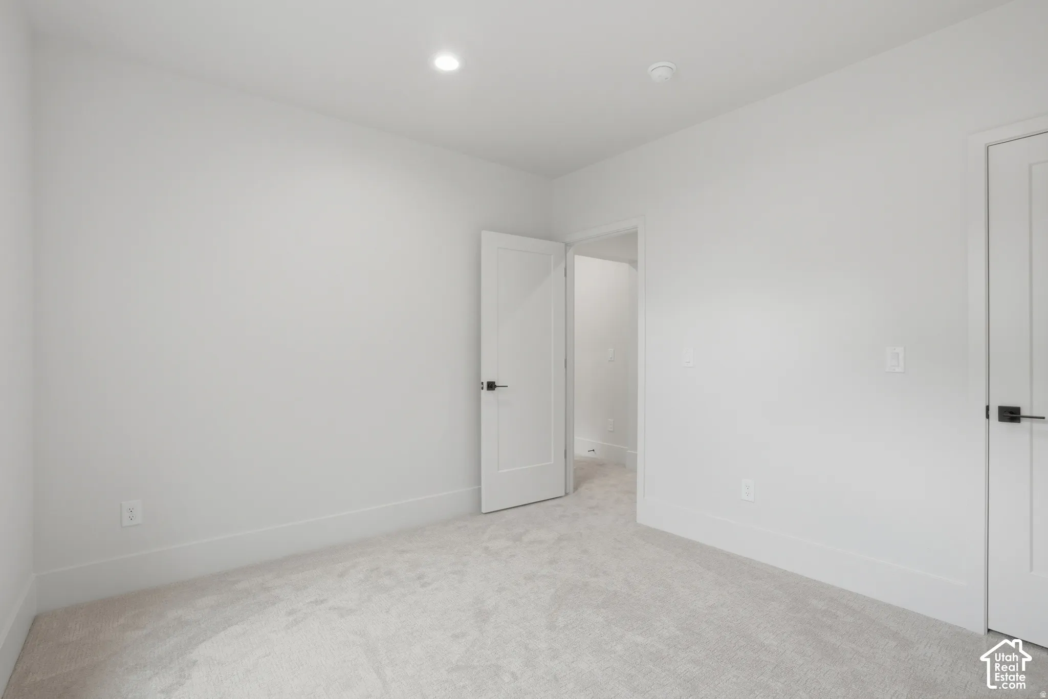 Neutral wall tones, wall-to-wall carpeting, recessed ceiling lighting, and solid-core interior doors with matte black hardware