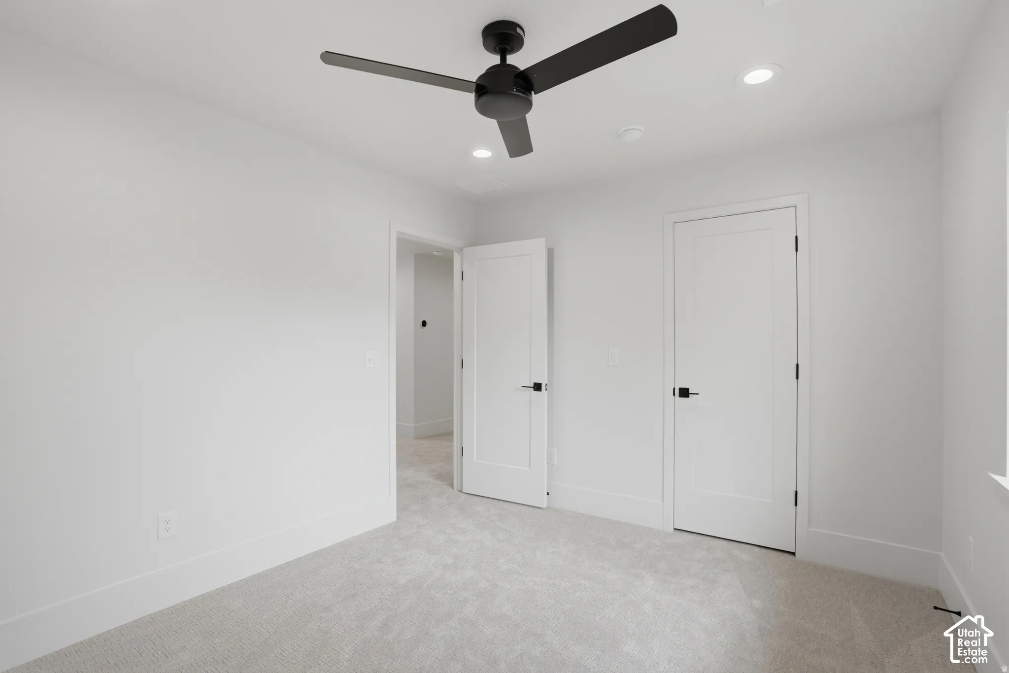 Interior space featuring neutral wall-to-wall carpeting, a matte black three-blade ceiling fan, recessed lighting, and white shaker-style interior doors with matte black hardware