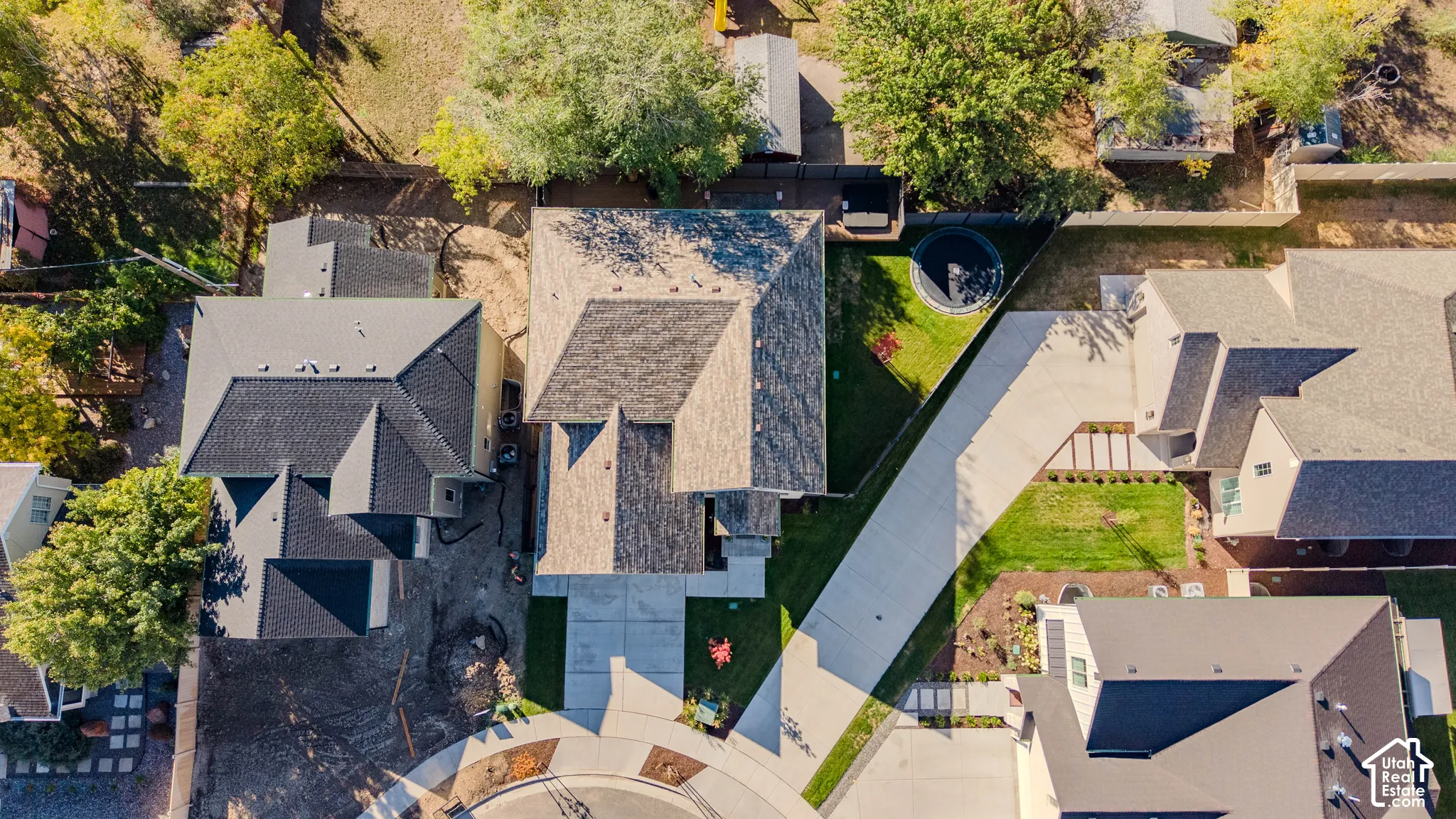 Aerial perspective featuring a multi-pitched asphalt shingle roof, concrete driveway, and established landscaping