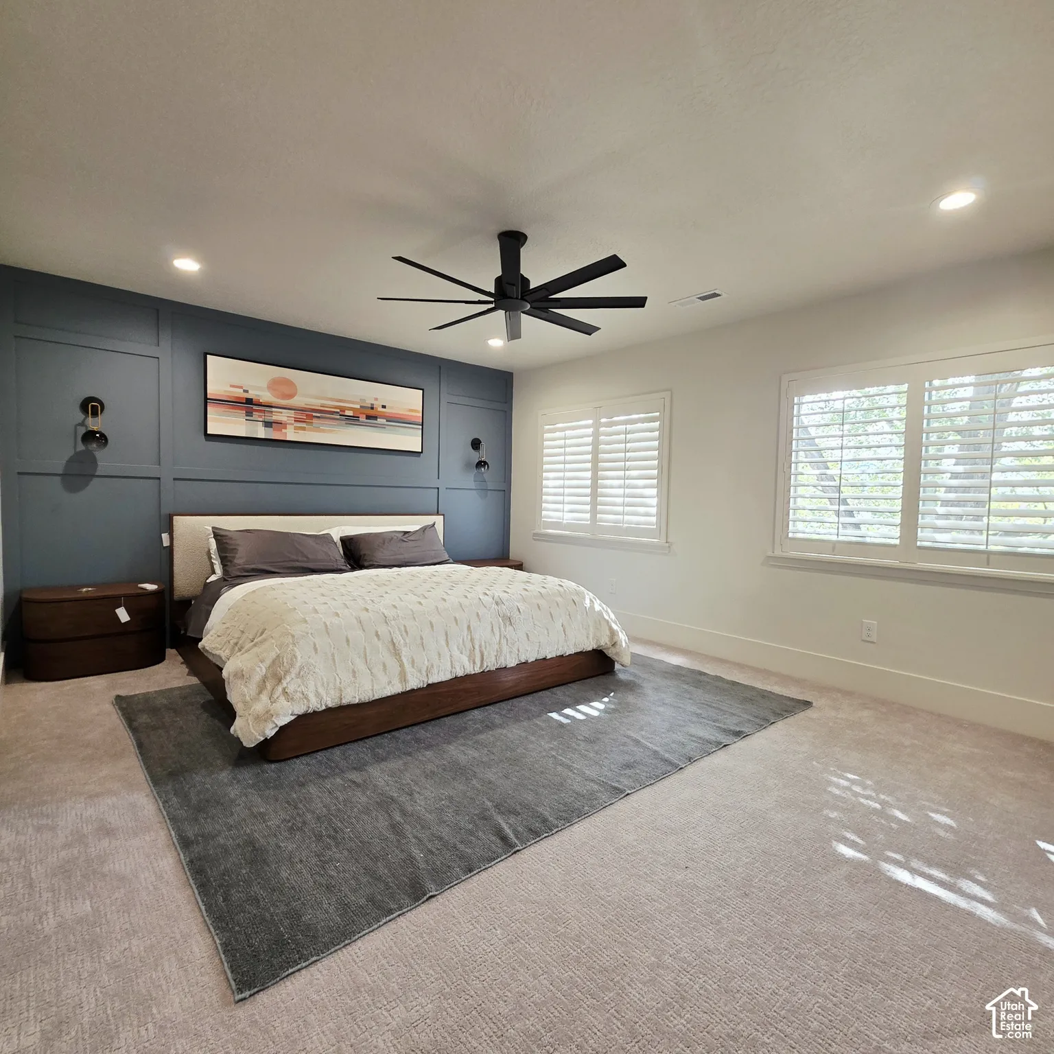 Accent wall with decorative moulding, recessed lighting, matte black ceiling fan, and plantation shutters