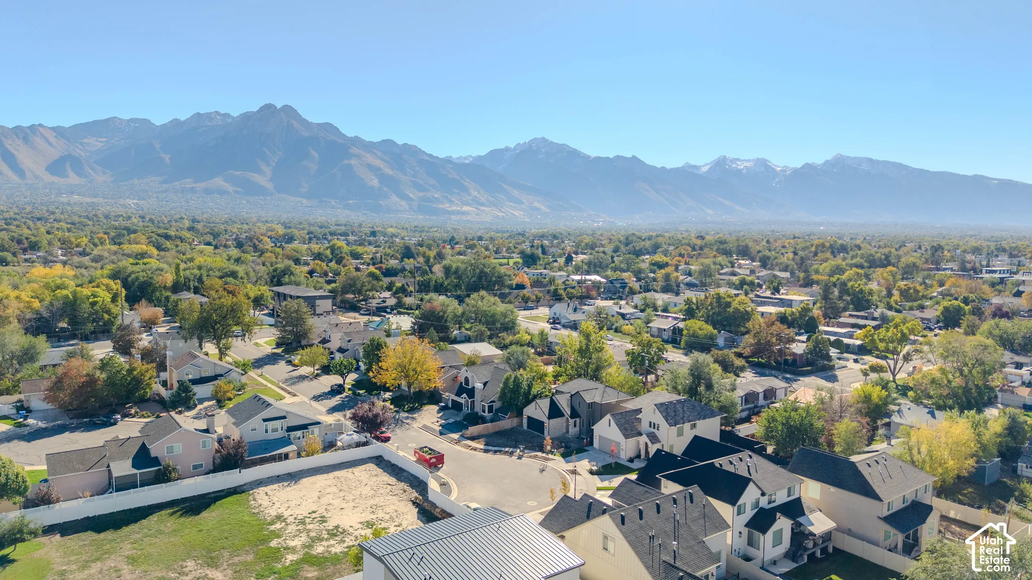 Aerial perspective featuring a mountainous backdrop, established tree canopy, and residential street grid
