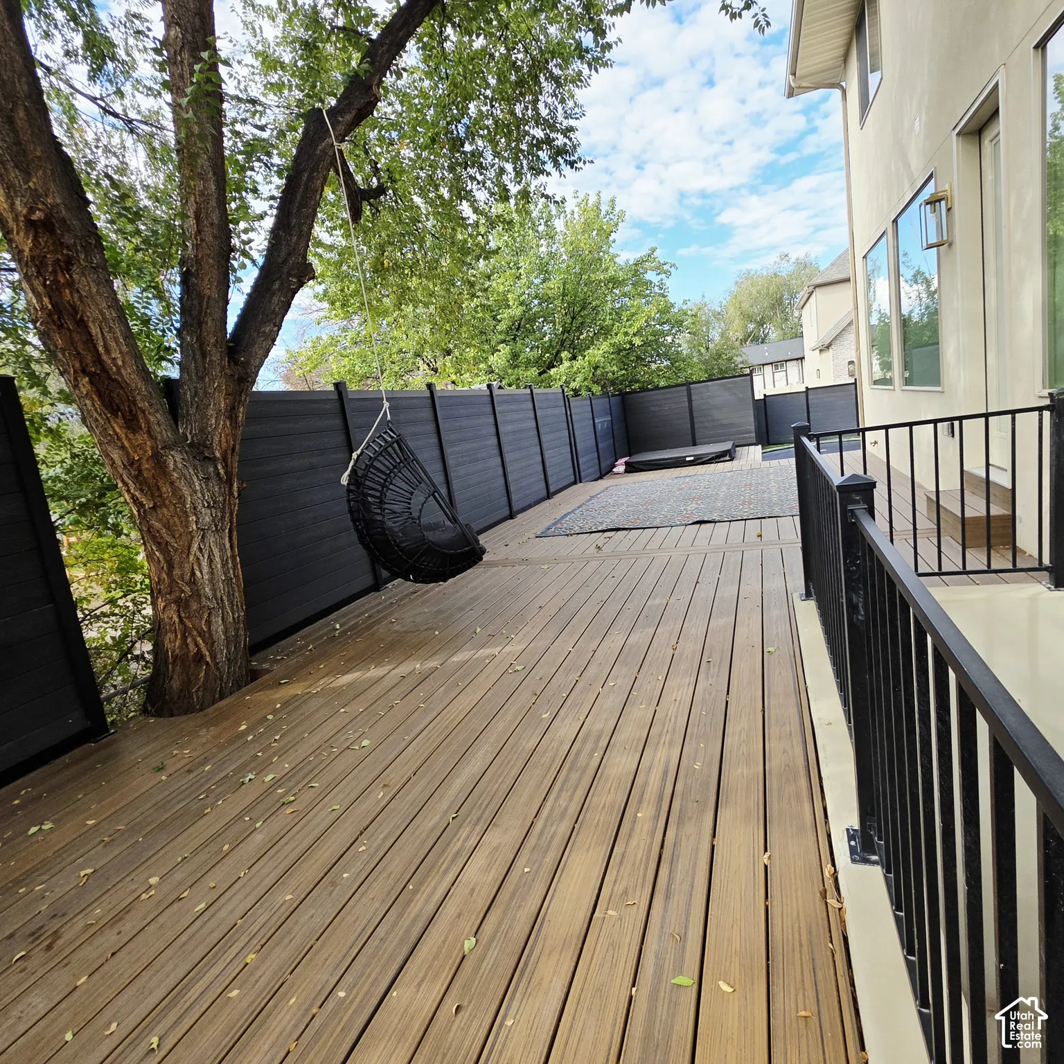 Exterior deck featuring horizontal wood-finish planks, black metal railings, and a privacy fence