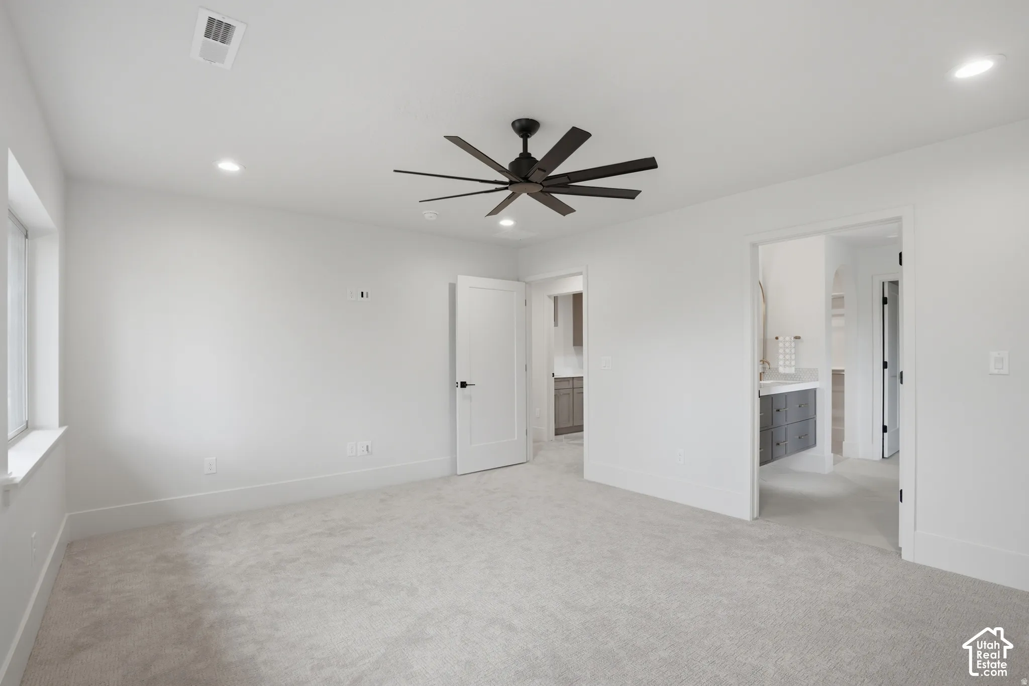 Neutral-toned wall-to-wall carpeting, recessed ceiling lighting, and a multi-blade matte black ceiling fan