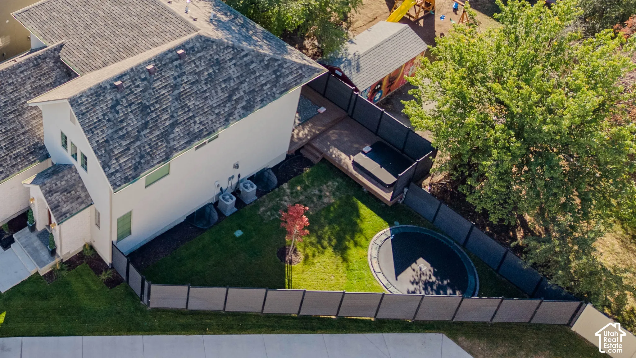 Backyard featuring a composite deck, an in-ground spa, a lawn, mature trees, and perimeter privacy fencing