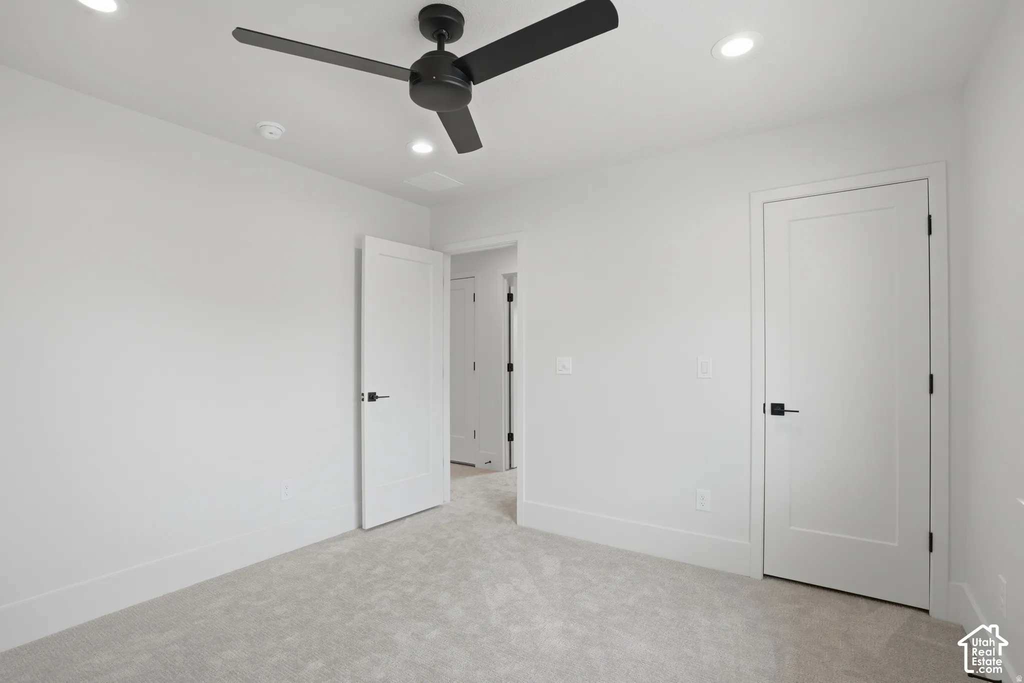 Room featuring recessed lighting, a matte black three-blade ceiling fan, neutral wall-to-wall carpeting, and solid-core interior doors with matte black hardware