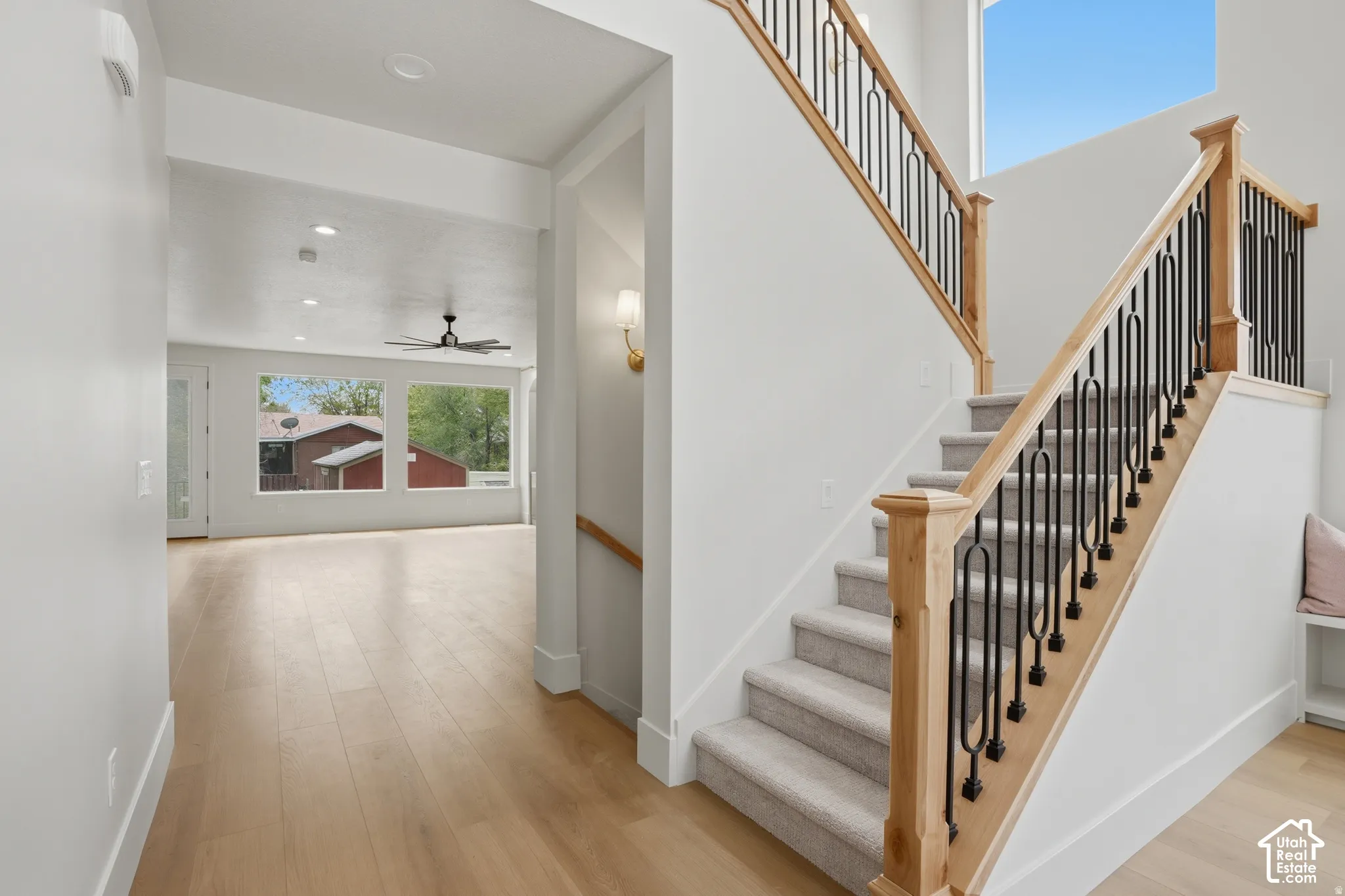 Staircase featuring light wood handrails, decorative metal balusters, and carpeted treads