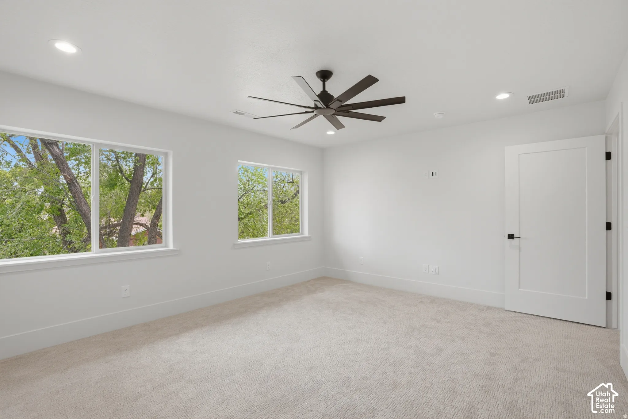 Neutral-toned carpeting, multi-blade ceiling fan, recessed lighting, and white interior doors with matte black hardware
