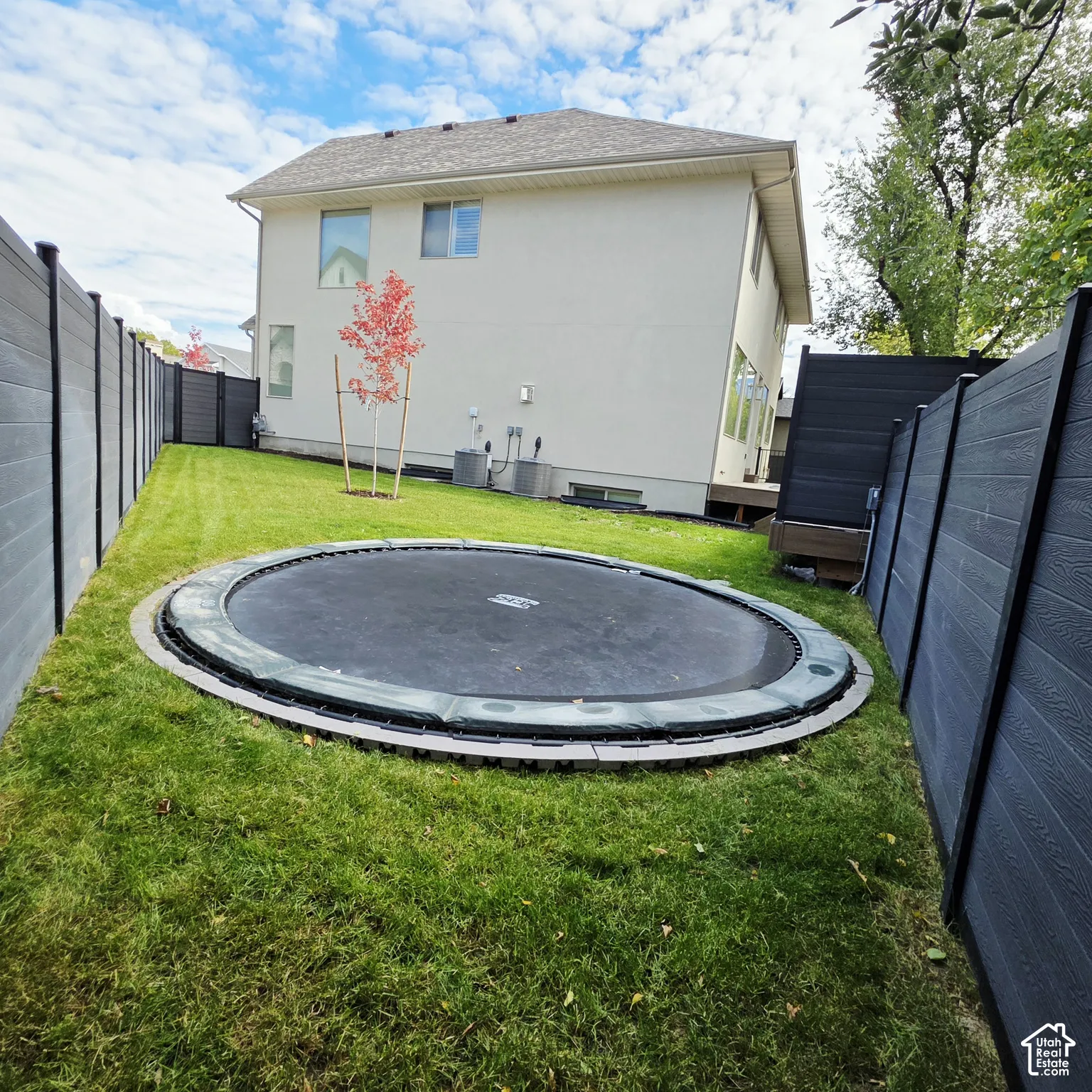 Rear yard featuring a tall, dark-toned composite privacy fence and a leveled lawn area