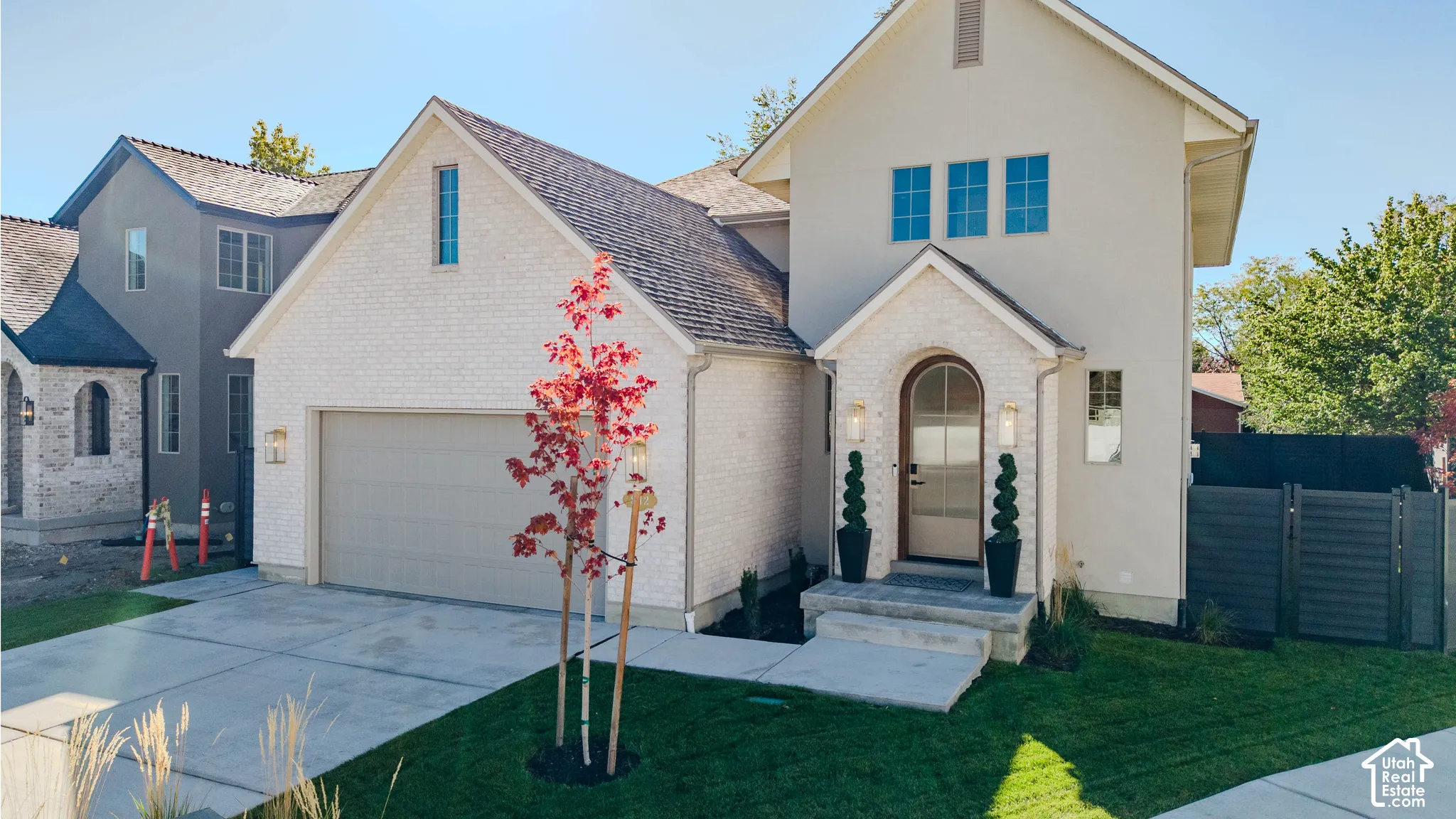 Multi-gabled exterior featuring light-toned masonry, stucco finish, arched entry, and a concrete driveway
