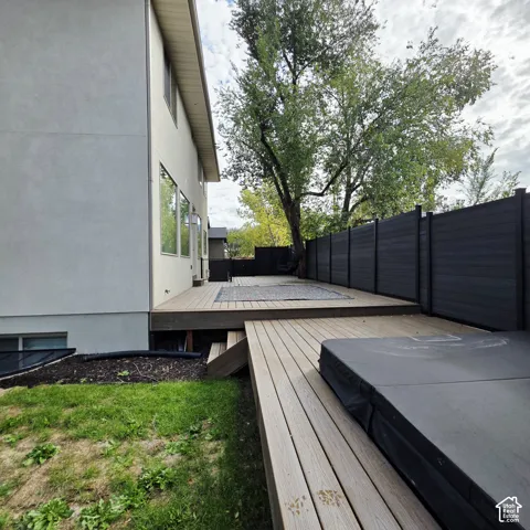 Multi-level composite decking, dark-toned privacy fencing, and built-in hot tub