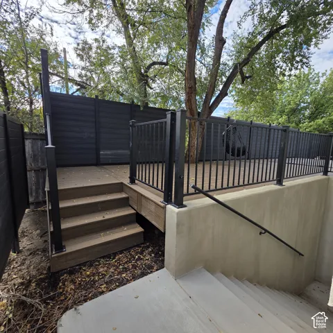 Elevated deck featuring composite decking, black metal baluster railings, and a solid black privacy screen